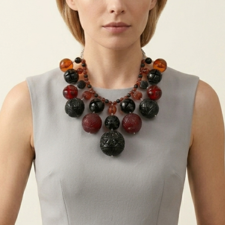 Woman wearing a gray dress with a colorful necklace against a plain background