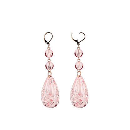 A pair of dangling earrings with faceted light pink teardrop beads and three smaller round pink beads, suspended from gold-tone hooks on a plain white background.