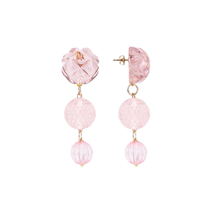 A pair of pink drop earrings featuring textured and faceted glass beads in shades of light pink, suspended from gold-tone posts on a solid white background.