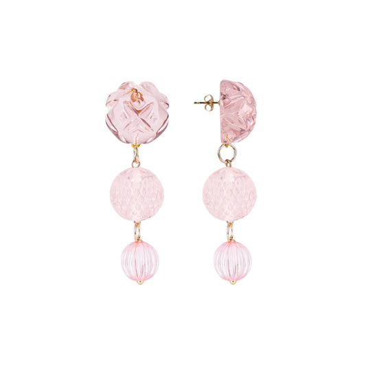 A pair of pink drop earrings featuring textured and faceted glass beads in shades of light pink, suspended from gold-tone posts on a solid white background.