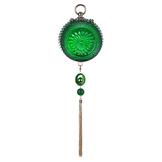 Green cut glass inspired round clutch bag with gold tone tassel and a hanging loop at the top, a dangling green bead, a smaller green bead, and a long metallic tassel, shown against a plain white background.